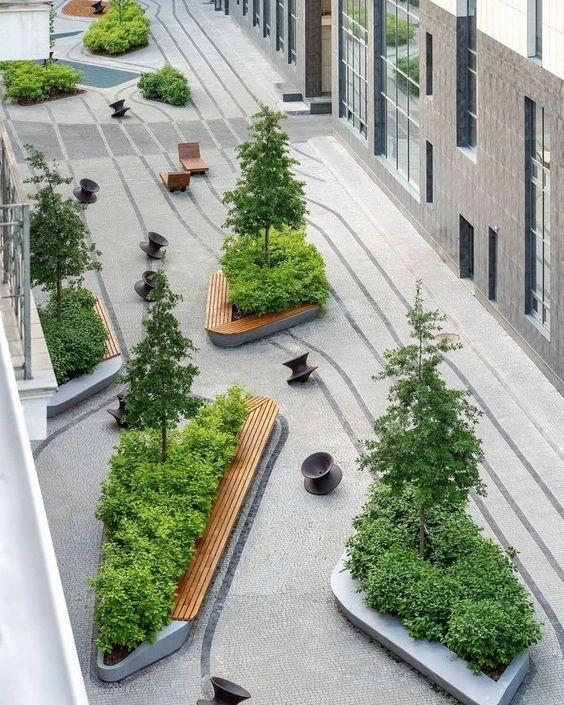An aerial view of a landscaped communal courtyard with raised planters, seating and trees between buildings