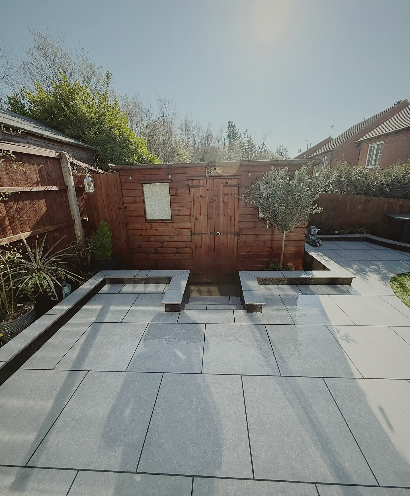 A porcelain courtyard with built-in bench seating and an olive tree