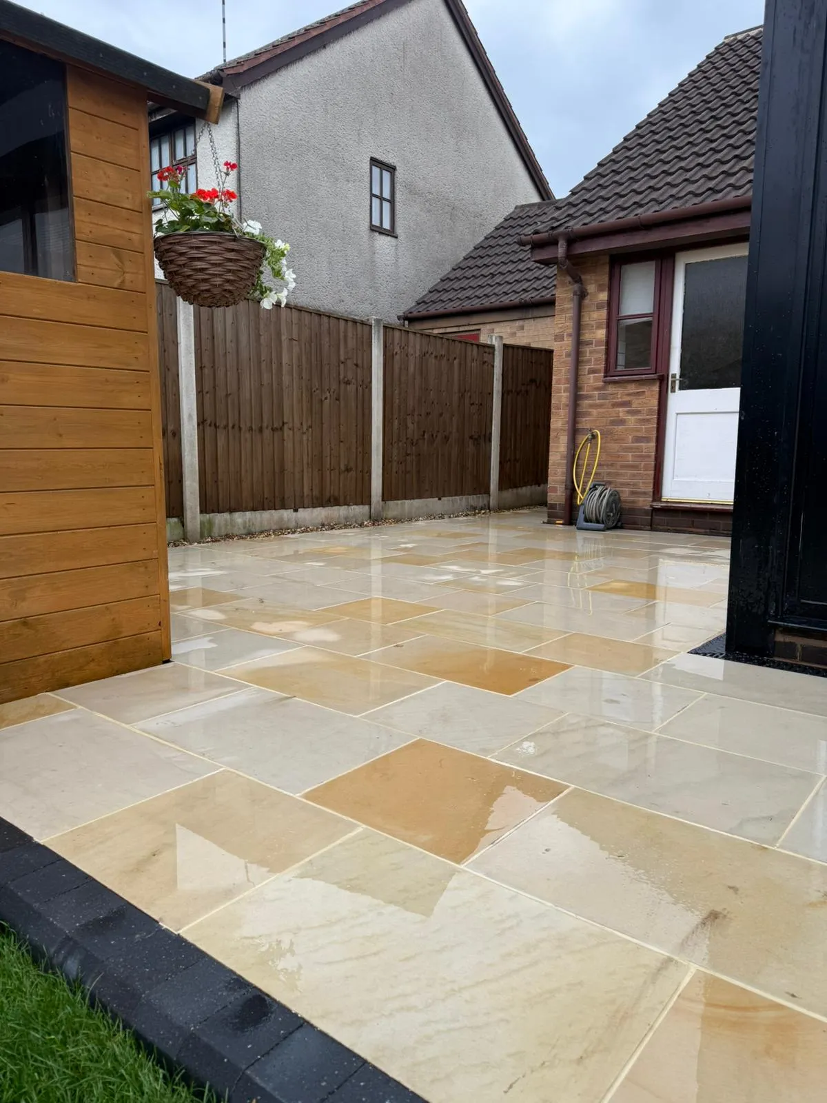 Freshly laid sandstone paving with charcoal edging in a rear garden